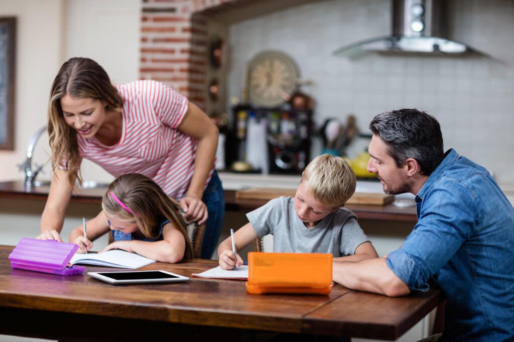 Vierköpfige Familie sitzt am Tisch und macht Hausaufgaben